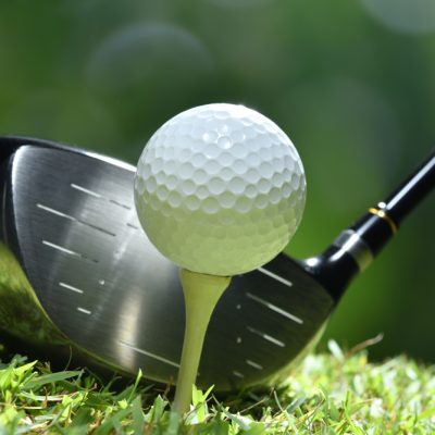 Golf ball on green grass ready to be struck on golf course background